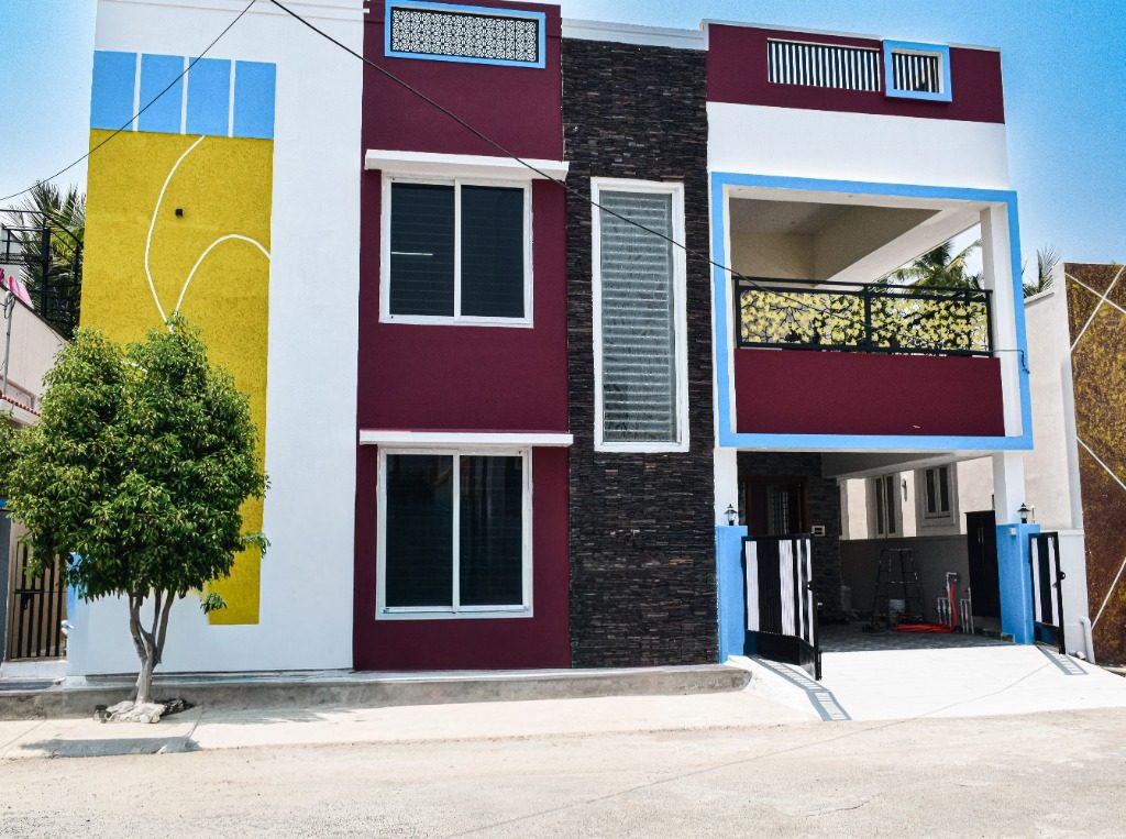 Two-story multi-tone duplex with vertical stone cladding, yellow accent facade, and balcony jali railing